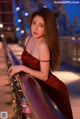 A woman in a red dress leaning on a railing.