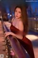 A woman in a red dress leaning on a railing.