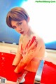 A woman with blood on her body sitting in a bathtub.