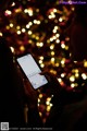 A person holding a cell phone in front of a Christmas tree.