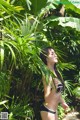 A woman in a black and white bikini standing in the jungle.