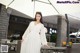 A woman in a white dress standing under an umbrella.