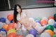 A woman in a white lingerie sitting on a bed of balloons.