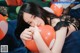 A woman laying on top of a bed holding a red balloon.