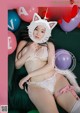 A woman in a cat costume sitting on a couch with balloons.