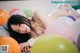 A woman laying on top of a pile of balloons.