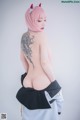 A woman with pink hair and a tattoo on her back.