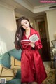 A woman in a red robe holding a book.