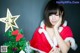 A woman in a santa claus outfit posing next to a Christmas tree.