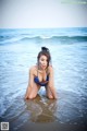 A woman in a blue bikini sitting in the water.