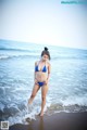 A woman in a blue bikini standing in the ocean.