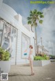 A woman in a white dress standing in front of a building.