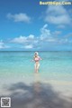 A woman in a bikini standing in the ocean.