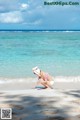 A little girl in a pink bikini playing on the beach.