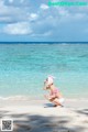 A woman in a pink bikini sitting on a beach.