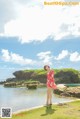 A woman in a red dress standing by the water.