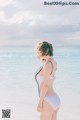 A woman in a white bikini standing on the beach.