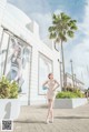 A woman in a white dress standing in front of a building.