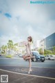 A woman in a beige dress is standing on the street.