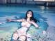 A woman in a white bathing suit sitting in a pool.