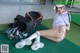 A woman sitting on the ground next to a golf bag.