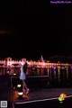 A woman in a blue dress standing on a dock at night.