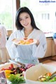 A woman holding a plate of food in front of a table.