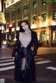 A woman in a black leather coat standing on a city street.