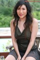 A woman in a black dress sitting on a wooden bench.