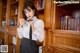 A woman in a white shirt and black tie standing in front of a bookcase.