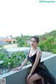 A woman in a black dress sitting on a ledge.