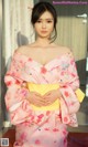 A woman in a pink kimono posing for a picture.