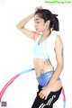 A woman in a blue top and black pants holding a hula hoop.