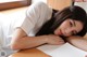 A woman laying on top of a wooden table next to a window.