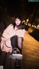 A woman sitting on a wooden bench at night.