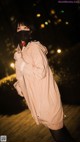 A woman wearing a face mask standing on a boardwalk at night.