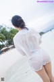 A woman in a white shirt is standing on the beach.