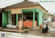 A woman standing in front of a fruit stand on a street corner.