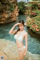 A woman in a white bikini standing in a pool.