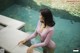 A woman in a pink bodysuit standing next to a pool.