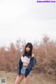 A woman in a white top and denim shorts posing for a picture.