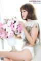 A woman sitting on a couch holding a vase of flowers.