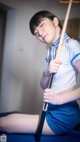 A woman in a blue and white uniform holding a pool cue.