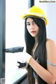 A woman wearing a hard hat and holding a drill.