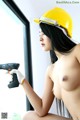 A woman in a hard hat holding a drill.