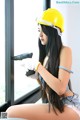 A woman wearing a yellow hard hat and white gloves.