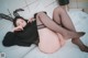 A woman laying on a bed wearing a black sweater and stockings.