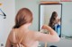 A woman brushing her hair in front of a mirror.