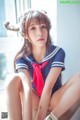 A woman in a sailor outfit sitting on a window sill.