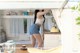 A woman in a white top and blue shorts standing in a kitchen.